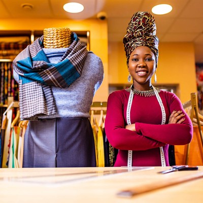 A clothes designer smiling broadly by her mannequin