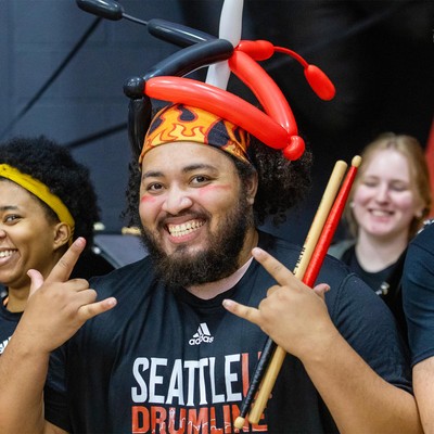 A smiling man with red and black balloons on his head