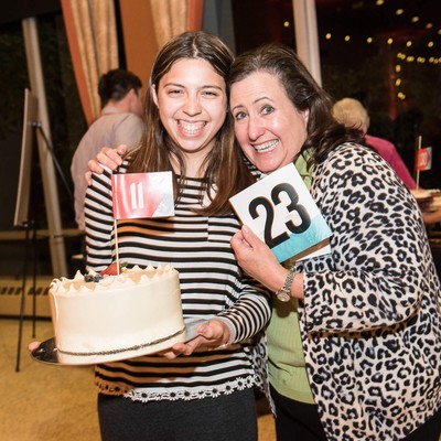 Two women holding a cake.
