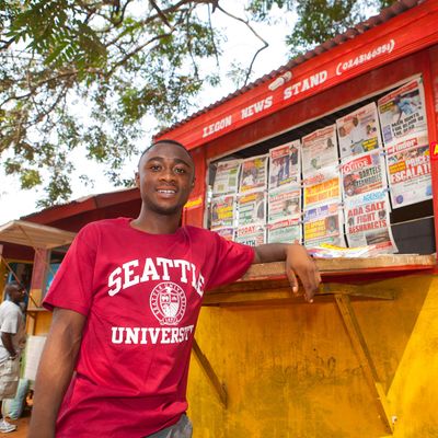 Photo of student in Seattle University shirt in front of newsstand in Ghana