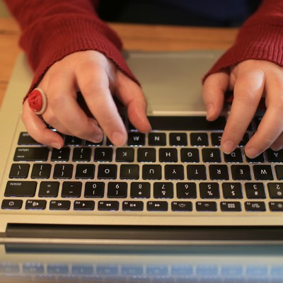 A woman typing on a laptop computer.