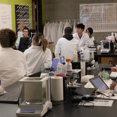 A group of people in lab coats in a classroom.