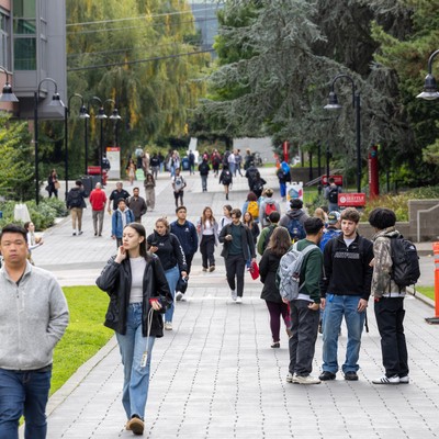 A group of people walking down a sidewalk in front of a building.