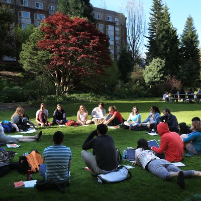 A group of people sitting on grass in a park.