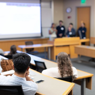 Audience members listening to a presentation in a lecture hall.