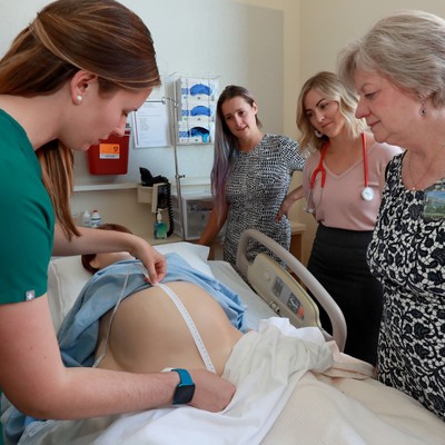 A group of people standing around a bed in a hospital.