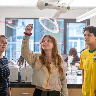 A group of people in a lab looking at a microscope.