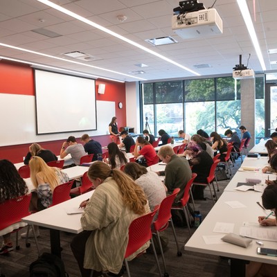 A group of people sitting at tables in a classroom.