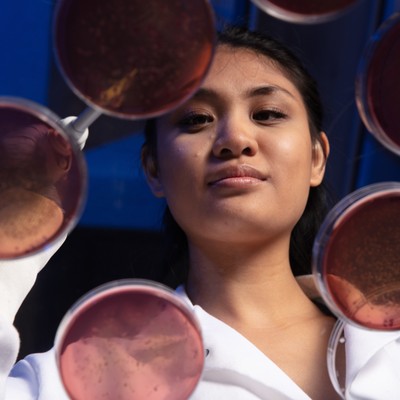 A woman in a lab coat working with petri dishes