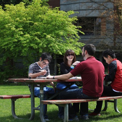 A group of people sitting at a picnic table in a grassy area.