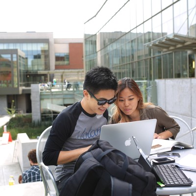 A group of people sitting at a table in front of a building.