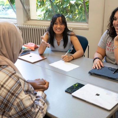 A group of people sitting around a table in a classroom.