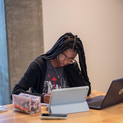 A woman sitting at a table looking at a laptop.