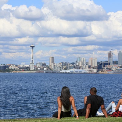 A group of people sitting on grass by water.