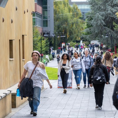 A group of people walking down a sidewalk.