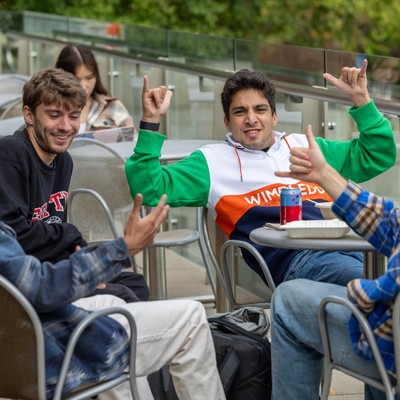 A group of people sitting at tables in an outdoor area.
