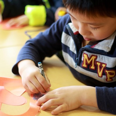 A group of children at a table making paper hearts.