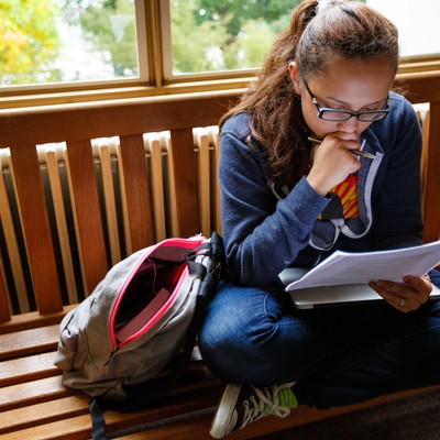 A student sits on a bench reading a book.