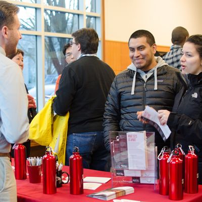 Prospective students talking with a representative at a table at an Open House event