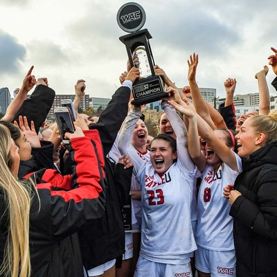Soccer players hoisting trophy