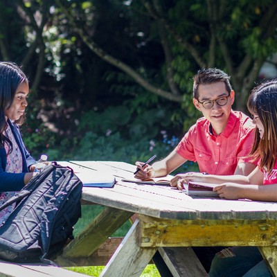 Three students study at outdoor table