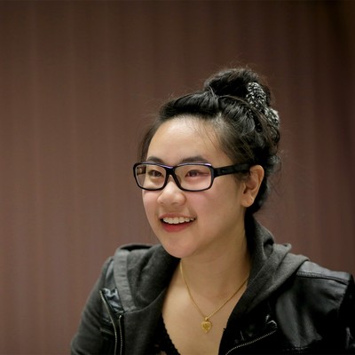 A student with glasses smiling into the distance.