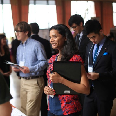 A student smiling amid other students at a career fair