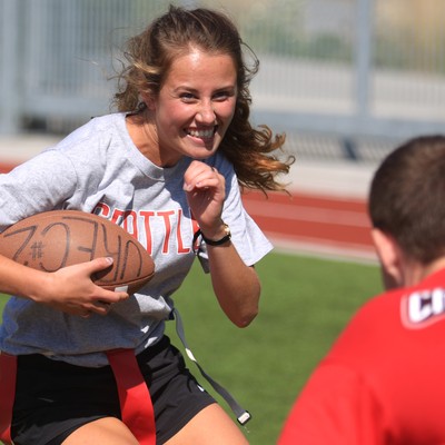 A girl is running with a football on a field.