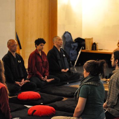Students with two monks seated in a circle meditating