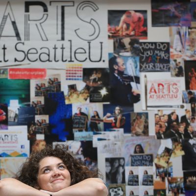 SU Student Meme Garcia infront of a gallery of photos