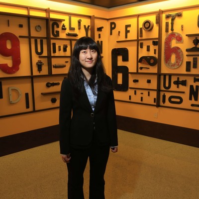 A woman standing in a room with many letters on the wall.