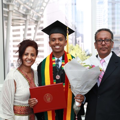 A man in a graduation cap and gown holding flowers and a woman in a cap and gown.