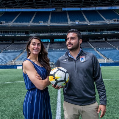 Two students on field with one holding soccer ball