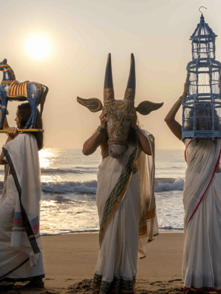 Three dancers with masks on beach