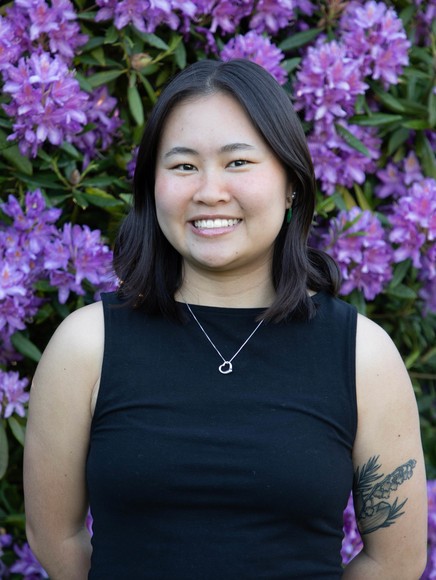 A woman standing in front of purple flowers