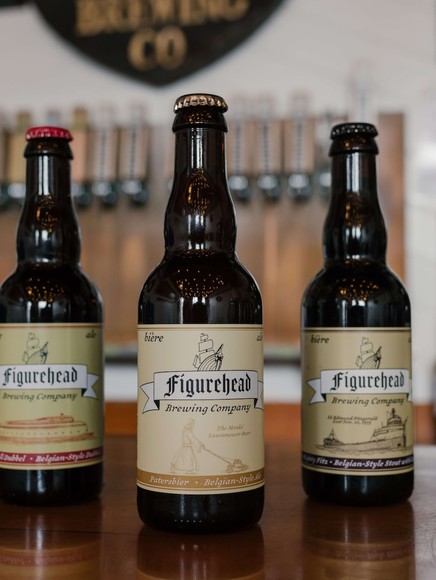 Five beer bottles in a row with Figurehead Brewing labels