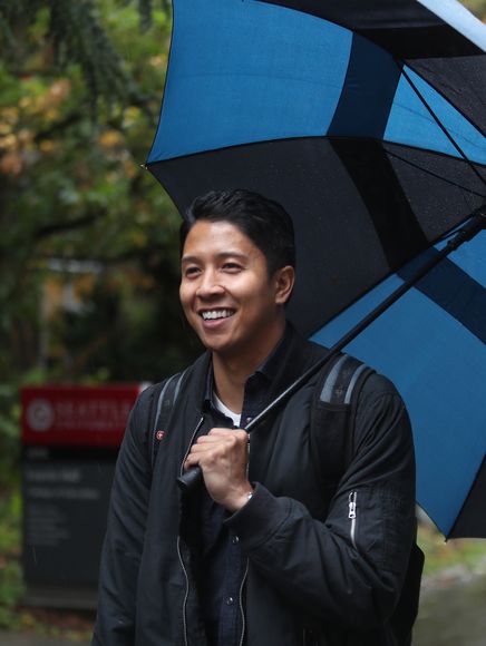 SU student Chris Mercurio smiling and holding an umbrella