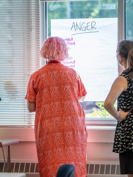 Three students stand at paper on window and write