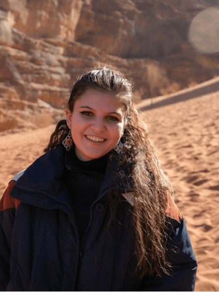 Ariana Siddiqui Dennis in front of a cliff in Jordan