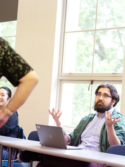 Student in class shrugging while another student laughs