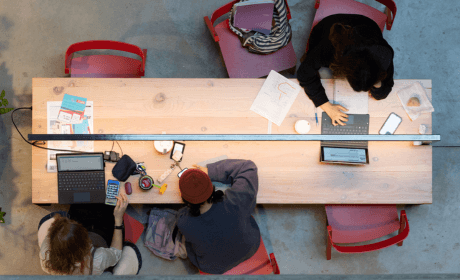 Overhead photo of people working at a table on computers