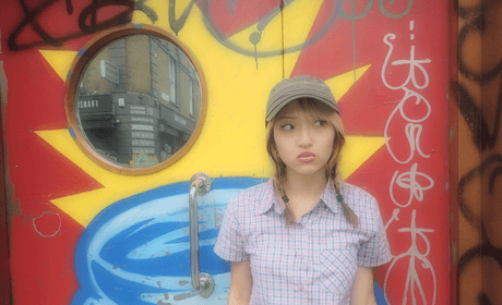 woman eyeing to the side in front of street art and traffic mirror