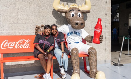 Two women posing on a bench at a Mariner's game