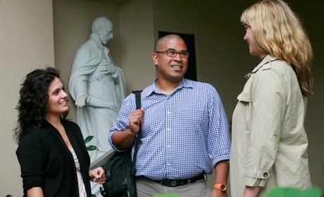 Three grad students talk in front of a building