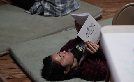 Student laying on the floor, reading a search  retreat bulletin