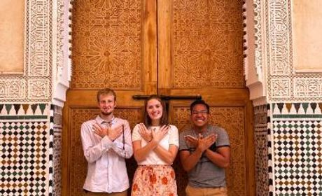 three Seattle U students making the Redhawk sign in a Moroccan doorway