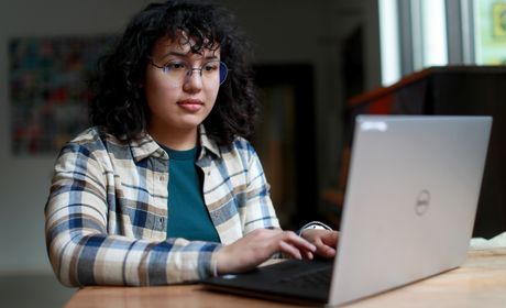 Student types on laptop in coffee shop