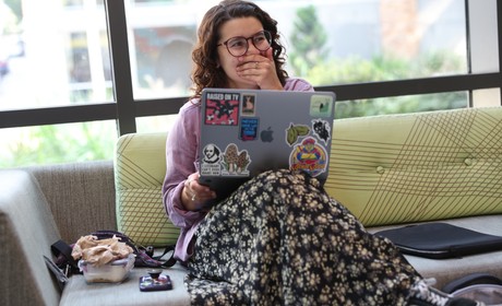 Student sits on interior bench with laptop