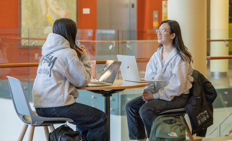 Image of students sitting down at a table on the second floor of Lemieux Library.