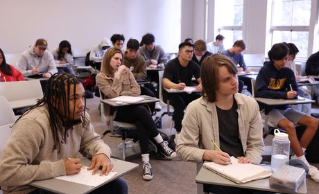 A classroom of students sitting in desks and listening